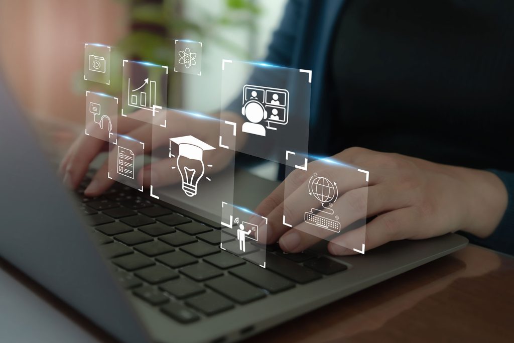 Hands typing on a laptop with online learning icons